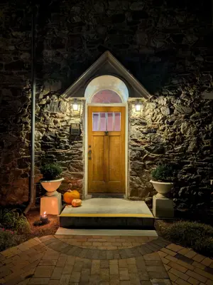 Evening front door of whitaker home being illumiated by porch light with pumpkins on stoop