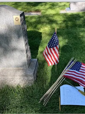 Veteran flags next to headstone with map and tool