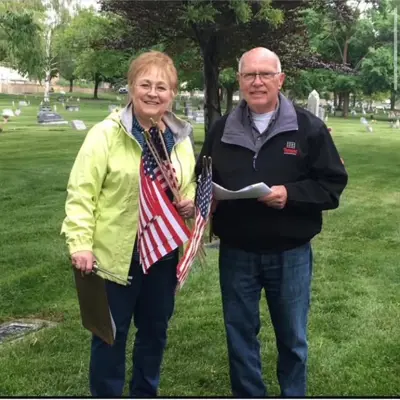 Couple with a bunch of american flags ready to be placed next to veteran graves in centerville cemetery