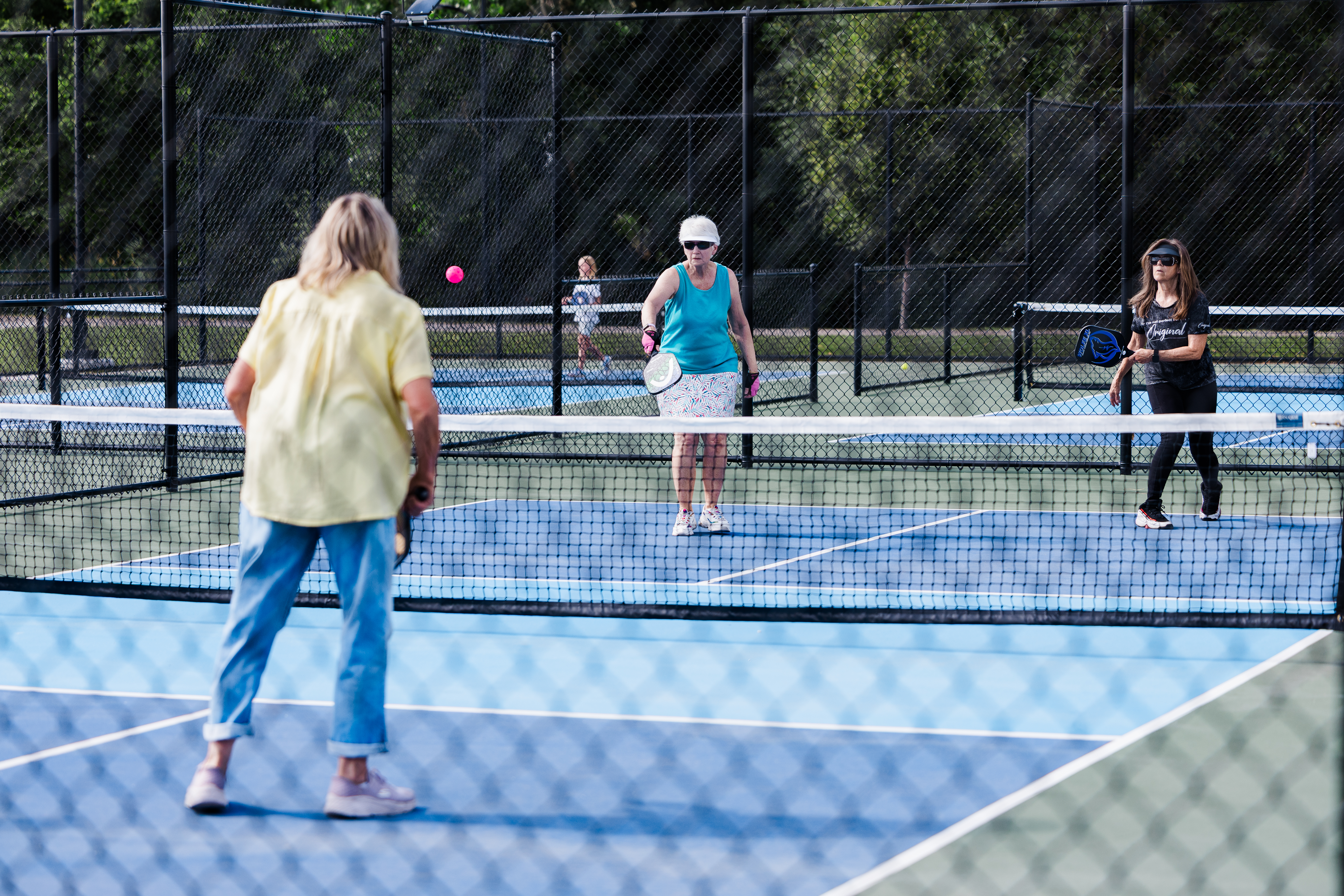 Adults playing pickleball on new blue court
