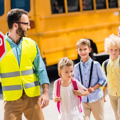 a man walking kids across the street in a cross walk