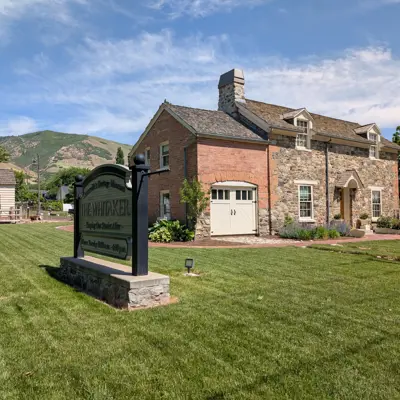 Historic Whitaker Home with museum sign, summer kitchen, and rolling centerville hills in the background on a sunny summer day