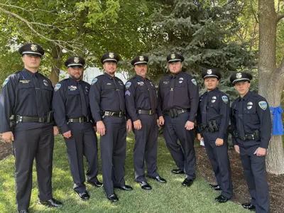 police officers standing in a half circle in their police dress uniforms. 