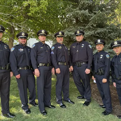 police officers standing in a half circle in their police dress uniforms. 