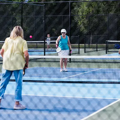 Adults playing pickleball on new blue court