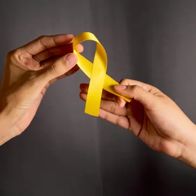 Two hands holding a yellow ribbon symbolizing suicide prevention