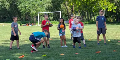 Youth playing dodgeball on grass in a park