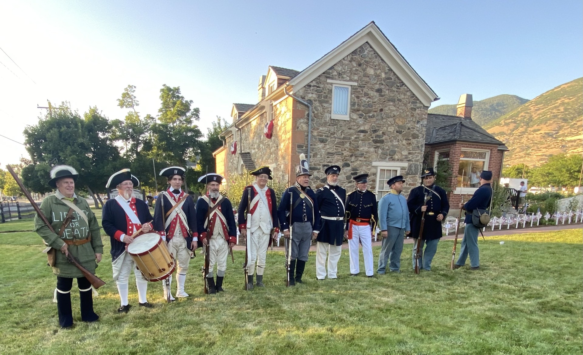 Revolutionaly war reenactors in uniform standing at attention outside of whitaker home