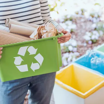 a person holding a bin that has a recycle logo on the outside