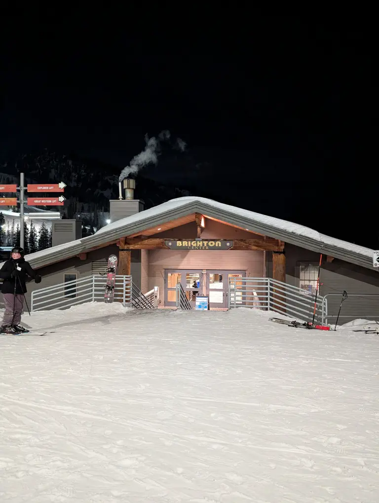 Outside the Brighton Nordic Center at Night with Snow in front of staris while lights eluminate from the building