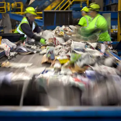 workers sorting through recycling materials down a conveyor belt